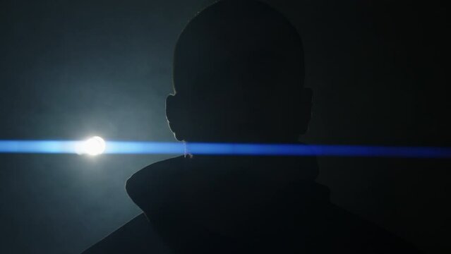 silhouette of a man in black clothes taking off his hood.