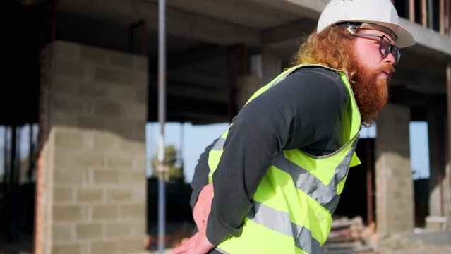 Red-haired worker injured at a construction site with body damage while working. Compensation accident claim.