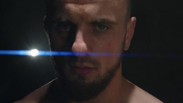 angry man looks into the camera and closes his eyes. fighter boxer sweat is flowing on his face. close-up anamorphic lens