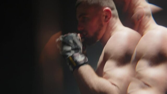 bifurcation effect in the mirror of a fighter punching a pear. a boxer with a bare muscular torso with pads on his fists punches a pear. shock. close-up