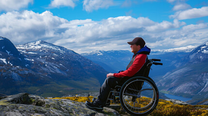 A man in a wheelchair enjoys a panoramic view of majestic mountains and a serene lake.