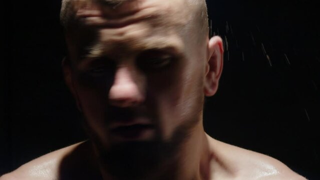 an aggressive fighter shakes his head from which sweat flows on his forehead. champion after a fight in mma boxing. close-up