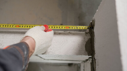Construction of a partition from blocks inside an apartment. Measuring walls with a tape measure...