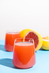 Grapefruit juice in a glass on blue background, space for text