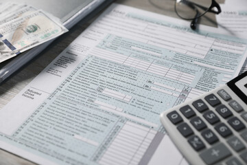 Payroll. Tax return forms, dollar banknotes and calculator on table, selective focus