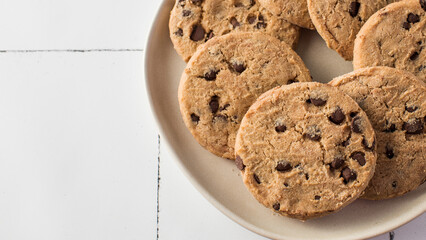Plate of chocolate chip cookies with extra chocolate chips on side. Copy space