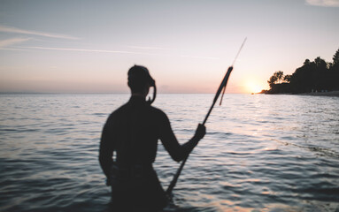 Selective focus of spearfisherman holds speargun and watch the sunset