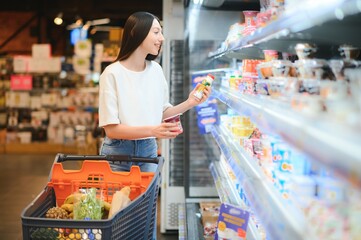 Young smiling happy woman 20s in casual clothes shopping at supermaket store with grocery cart