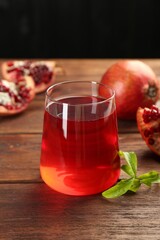 Tasty pomegranate juice in glass and fresh fruits on wooden table, closeup