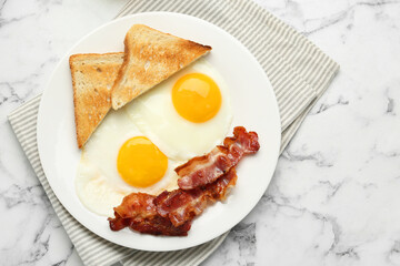 Delicious breakfast with sunny side up eggs on white marble table, top view