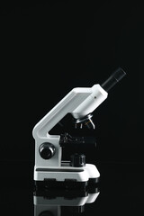 Modern medical microscope on black mirror surface