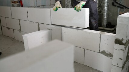 Workers build a light brick wall at a construction site. Wall building block. Builder. Hands of a...