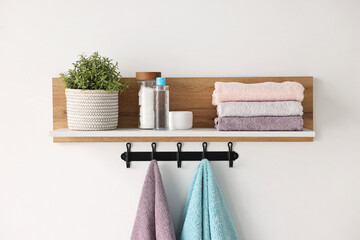 Clean towels, houseplant and toiletries on shelf indoors