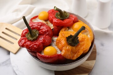 Delicious stuffed bell peppers with fried eggs on white marble table