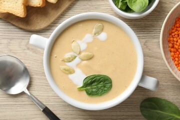Healthy cream soup high in vegetable fats served on wooden table, flat lay