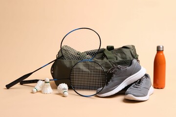 Badminton set, bag, sneakers and bottle on beige background