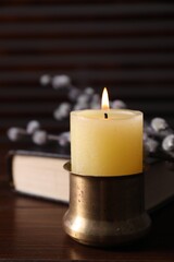 Burning candle on wooden table, closeup view