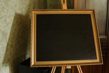 Blank blackboard with gold frame on the table in room.