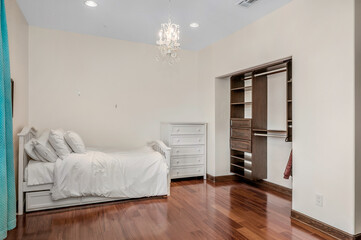 a white bed sitting on top of a wooden floor next to a closet