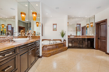 the large bathroom has a tub with glass doors and granite countertops