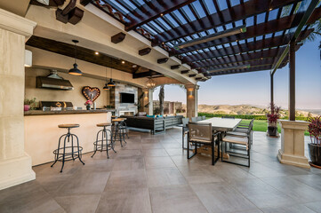 an outdoor kitchen with a large bar and two tables on the porch