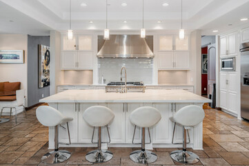 two white bar stools next to a large kitchen island