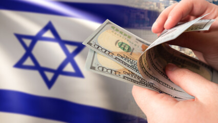 Money near Israeli flag. Dollars in hands. Concept financial assistance for Israel. Investing in...