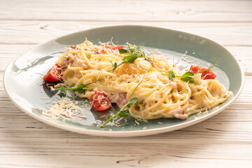Spaghetti pasta with carbonara sauce and pieces of bacon on a plate