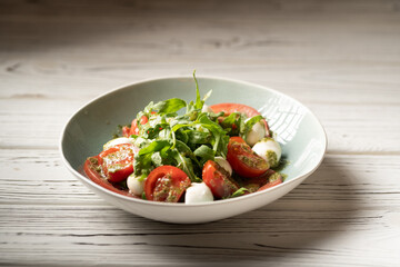 Italian caprese salad in restaurant. Fresh mozzarella, cherry tomatoes and basil leaf with pesto sauce. Organic and healthy food