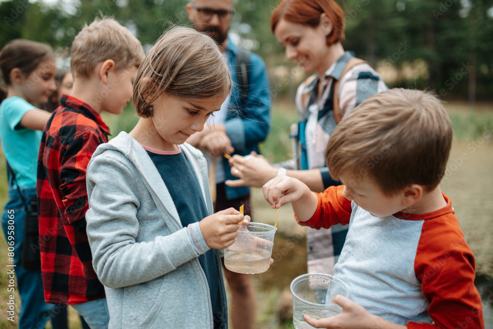 Poster Young students analyzing water quality, ph level with indicator strips during biology field teaching class. Female teacher during outdoor active education.