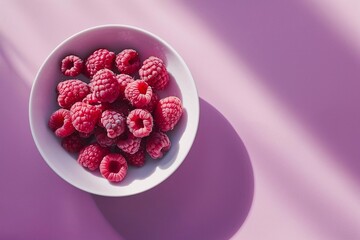 Raspberries in plate on pink background. Summer tasty berries.