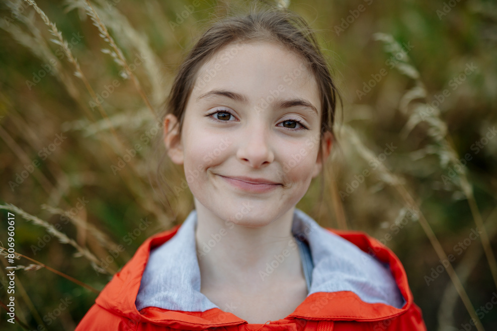 Wall mural portrait of beautiful young girl standing in nature, in the middle of tall grass, headshot. copy spa