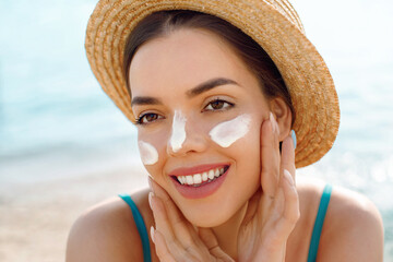 Woman smile applying sun cream on face. Skincare. Body Sun protection. sunscreen. Female in hat...