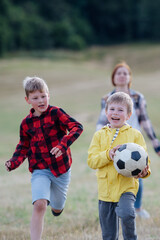 Fototapeta premium Young students playing with teacher outdoors, in nature, during field teaching class, running with ball. Dedicated teachers during outdoor active education.