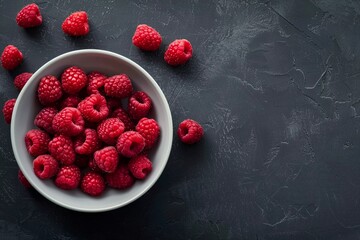 Raspberries in plate on dark background. Summer tasty berries.