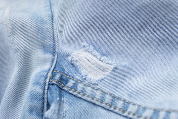 Light blue jean background. Denim seams. Denim fabric worn out. Textured background.