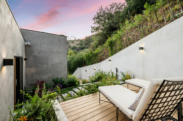 an outdoor patio with two lounge chairs at sunset over the hillside