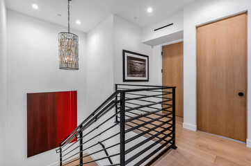 modern wooden staircase with black railing and white walls in entry