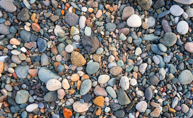 Multi-colored pebbles on a pebble beach, top view