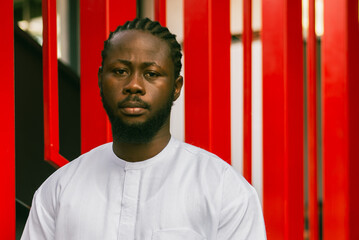 Cheerful male tourist portrait dress in white wear dashiki ethnic smiling at city street or small town background. African American travel model have free time. Millennial generation and gen z people