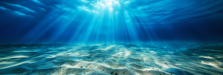Underwater seascape showing a sandy seabed with sunlight streaming through the water.