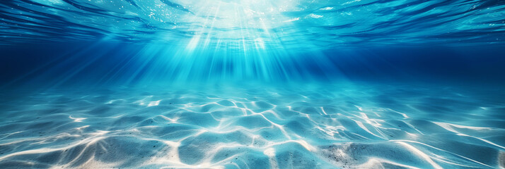A serene underwater view with sunbeams illuminating the sandy ocean floor through clear blue water.
