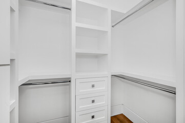 Fototapeta premium an empty closet with white shelves and white cabinets and a drawer