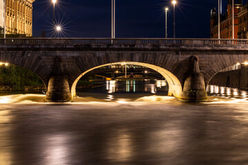 Stockholm, Sweden Fresh water from Lake Malaren rushes under the Norrbro bridge in the Norrstrom body of water downtown at night into the Baltic Sea.