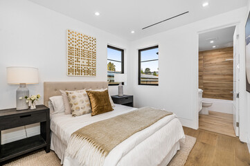 the bedroom features a large bed, hardwood flooring and white walls