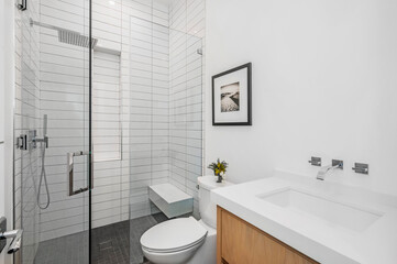 Fototapeta na wymiar the bathroom features white and black subway tile, wooden cabinetry and floor