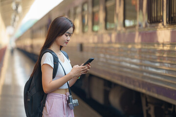 Asia woman traveler using phone while waiting for train, Travel and lifestyle concept.