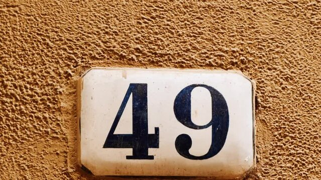 Number 49 (forty-nine) affixed to the exterior of a building, with an elegant, vintage and traditional appearance