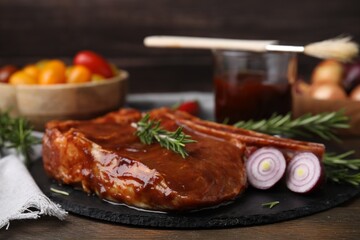 Tasty marinated meat, rosemary and onion on wooden table, closeup