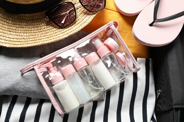Plastic bag of cosmetic travel kit and beach accessories in suitcase, top view